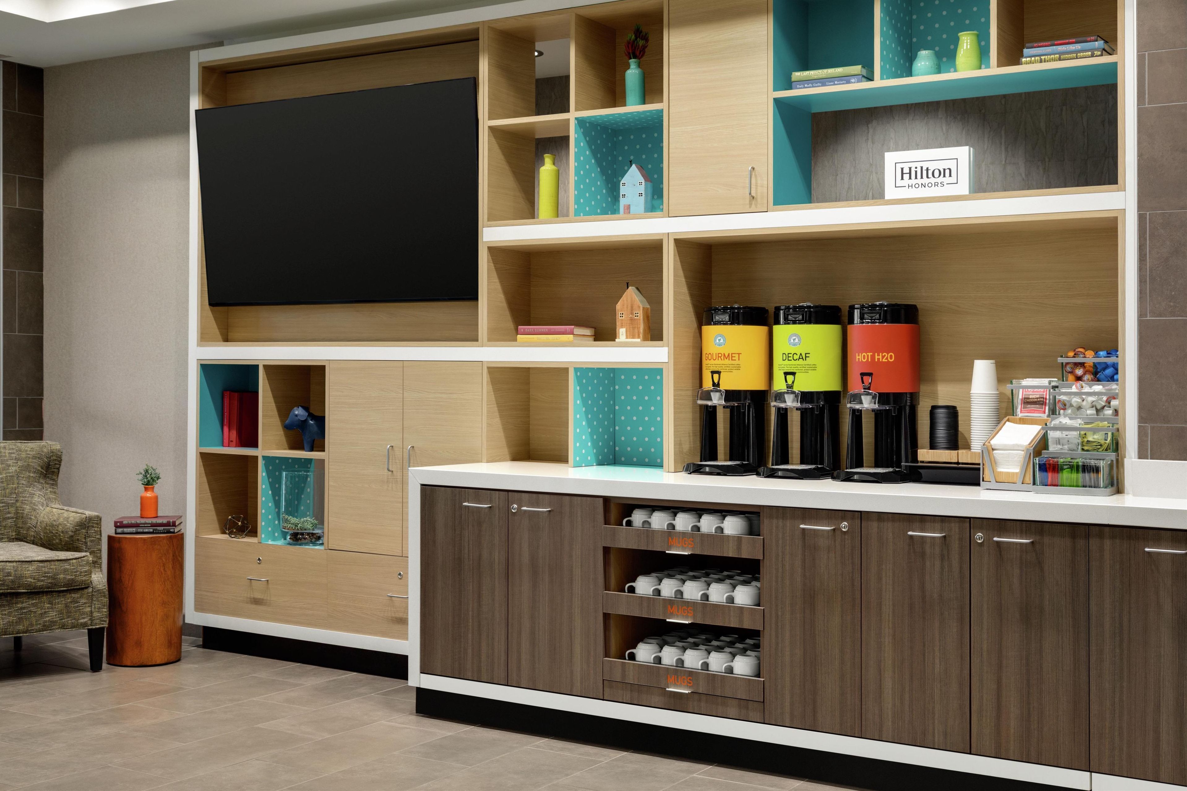 A hotel room with a minibar, a flat-screen TV, and a sign reading "Hilton Honors".