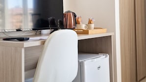 Un espace de bureau moderne comprenant un bureau, une chaise, un ordinateur et un petit réfrigérateur.