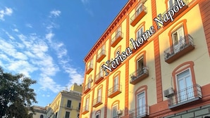 Un immeuble à plusieurs étages doté de balcons, un magasin Samsung et une enseigne « Vino Tre » au rez-de-chaussée.