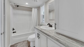 A bathroom with a bathtub, toilet, and sink. - Indian Point Cabin near SDC Table Rock Lake & Branson (Branson)