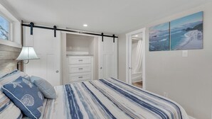 A bedroom with a bed, a nightstand, a wall-mounted lamp, a closet with a sliding door, and a beach-themed painting. - Indian Point Cabin near SDC Table Rock Lake & Branson (Branson)