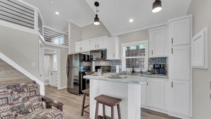 A modern kitchen with white cabinetry, a stainless steel refrigerator, a built-in microwave, and a coffee maker. - Indian Point Cabin near SDC Table Rock Lake & Branson (Branson)