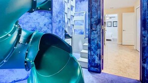 A spiral staircase leading to a second floor, a door to a room, and a large green structure. - Palm Paradise Haven (Four Corners)