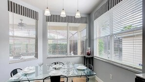 Un coin repas comprenant une table en verre, quatre chaises et trois lampes suspendues.