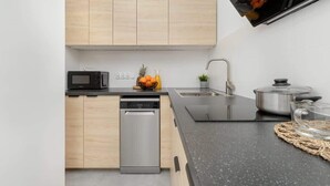 Eine moderne Küche mit Holzschränken, einem Geschirrspüler, einer Mikrowelle, einem Spülbecken und einem Edelstahlkochtopf.