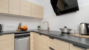Eine moderne Küche mit Holzausstattung, Geschirrspüler, Spüle, Herd und Mikrowelle.