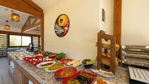 A buffet with various food items, a wooden chair, and a wall-mounted painting. - MARVELOUS SARIGERME (Sarigerme)