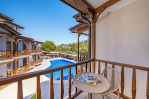 A balcony with a view of a swimming pool, wooden railings, and a table with a magazine. - MARVELOUS SARIGERME (Sarigerme)