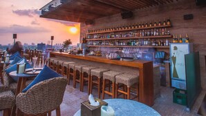 A rooftop bar with a city view, wooden bar stools, and a variety of bottles on shelves. - Landmark 81 Residences Luxury (Ho Chi Minh City)