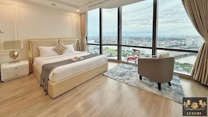 A spacious bedroom with a large bed, a nightstand, a chair, and a view of a cityscape through large windows. - Landmark 81 Residences Luxury (Ho Chi Minh City)