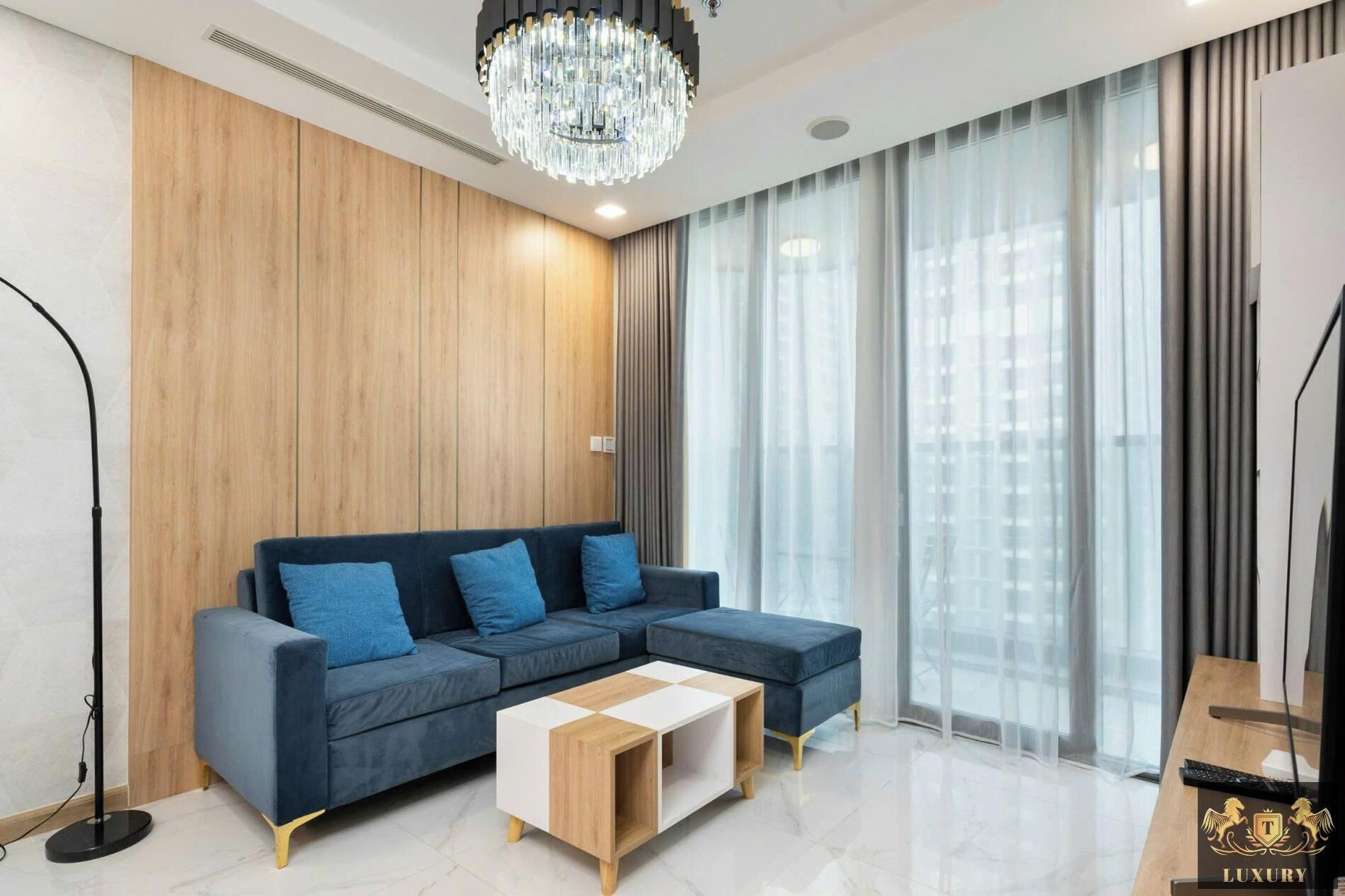A modern living room with a sectional sofa, a coffee table, and a chandelier.