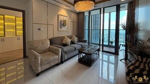 A modern living room with a sofa, a coffee table, and a chandelier. There is a large window with a city view. - Landmark 81 Residences Luxury (Ho Chi Minh City)