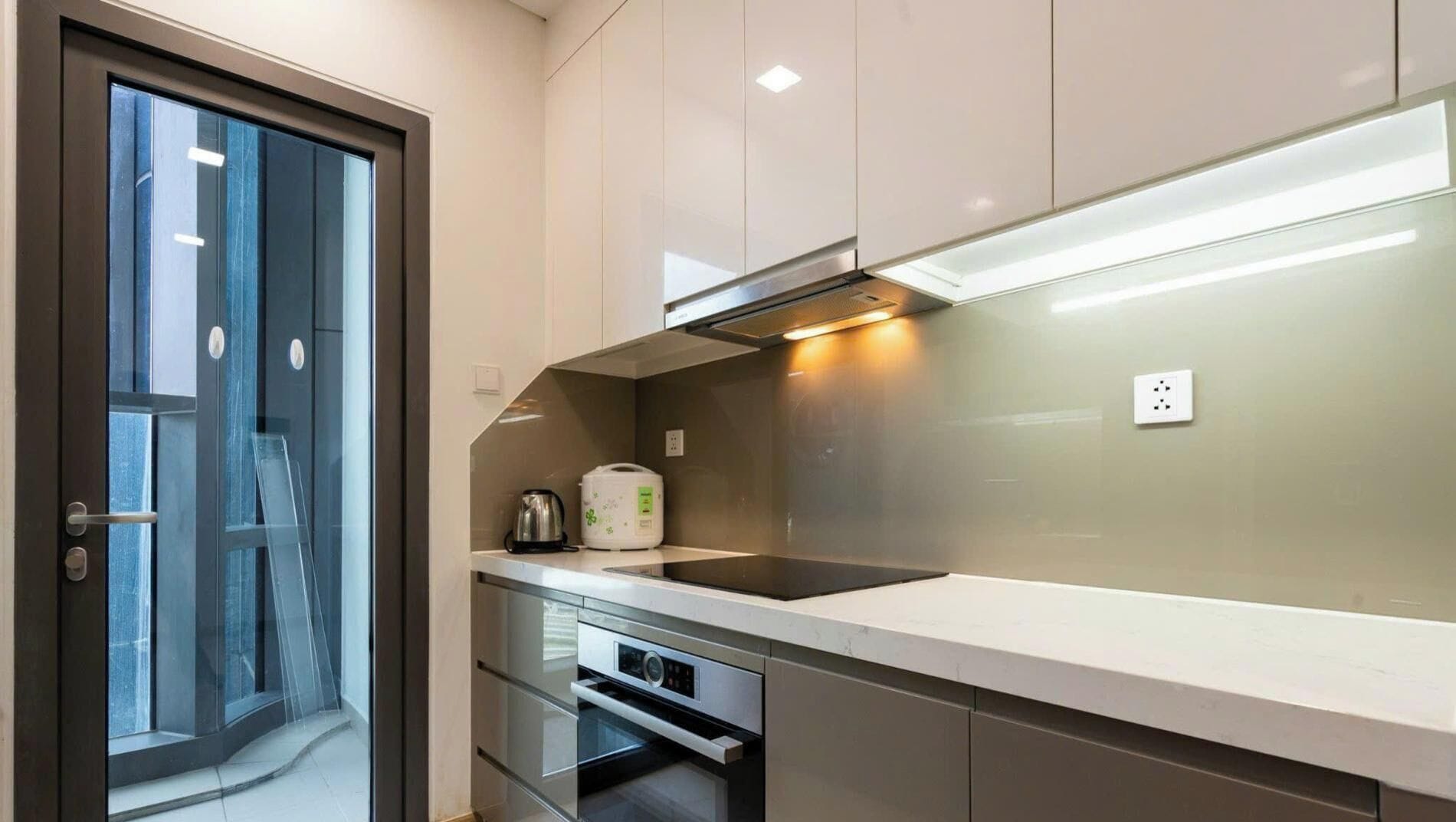 A modern kitchen with a built-in oven, a coffee maker, and a kettle on the counter.