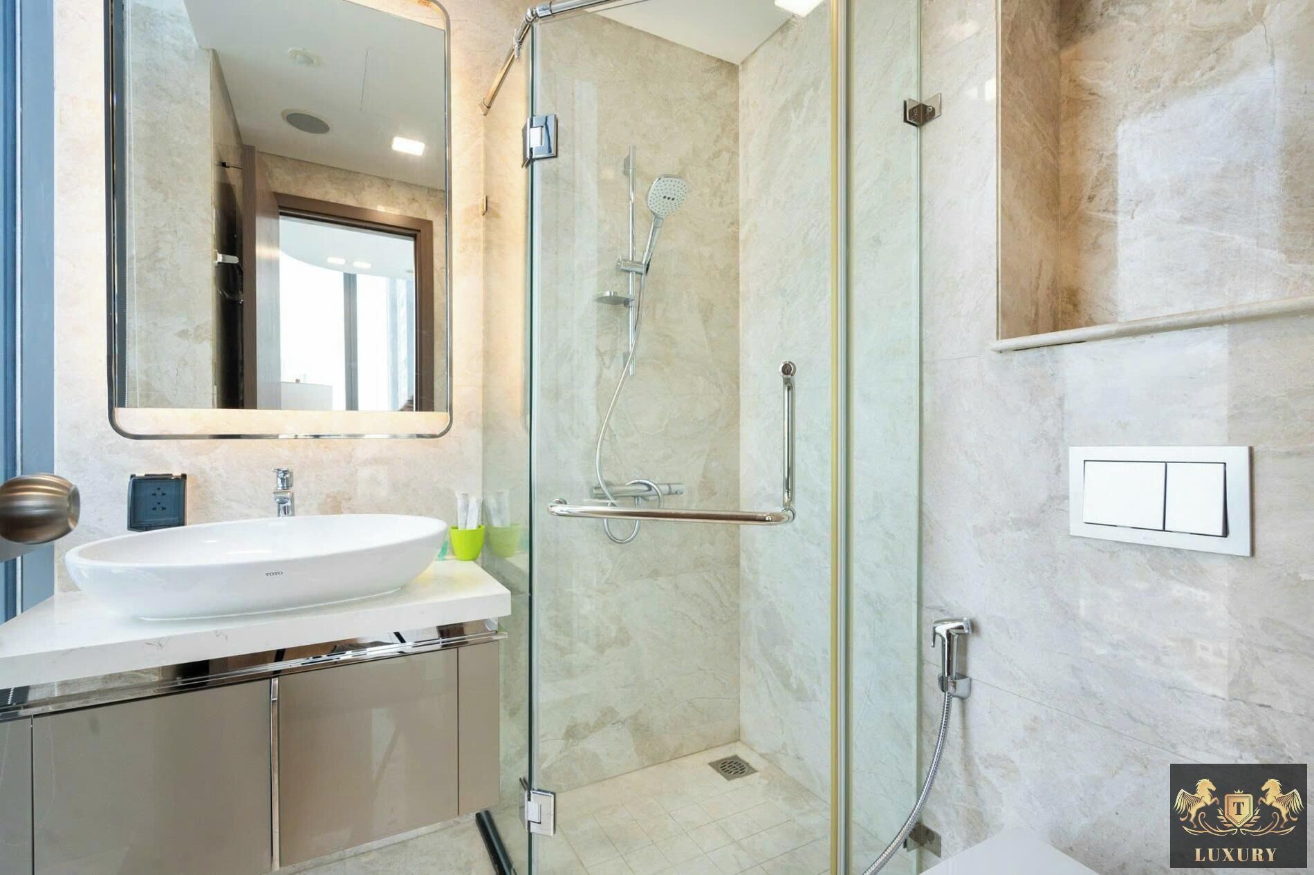 Et moderne badeværelse med en brusekabine i glas, en vask med et spejl over og et toilet.