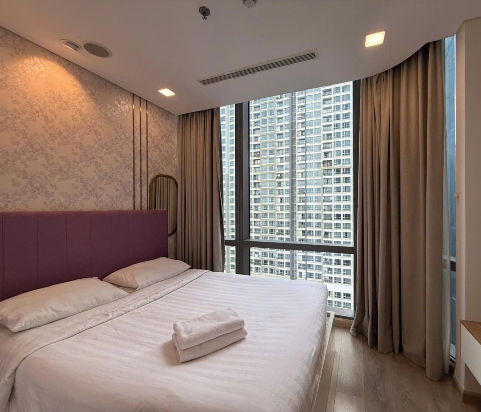Habitación de hotel con una cama grande, vistas a rascacielos y un diseño moderno.