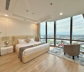 A spacious bedroom with a large bed, a nightstand, a chair, and a view of a cityscape through large windows. - Landmark 81 Residences Luxury (Ho Chi Minh City)