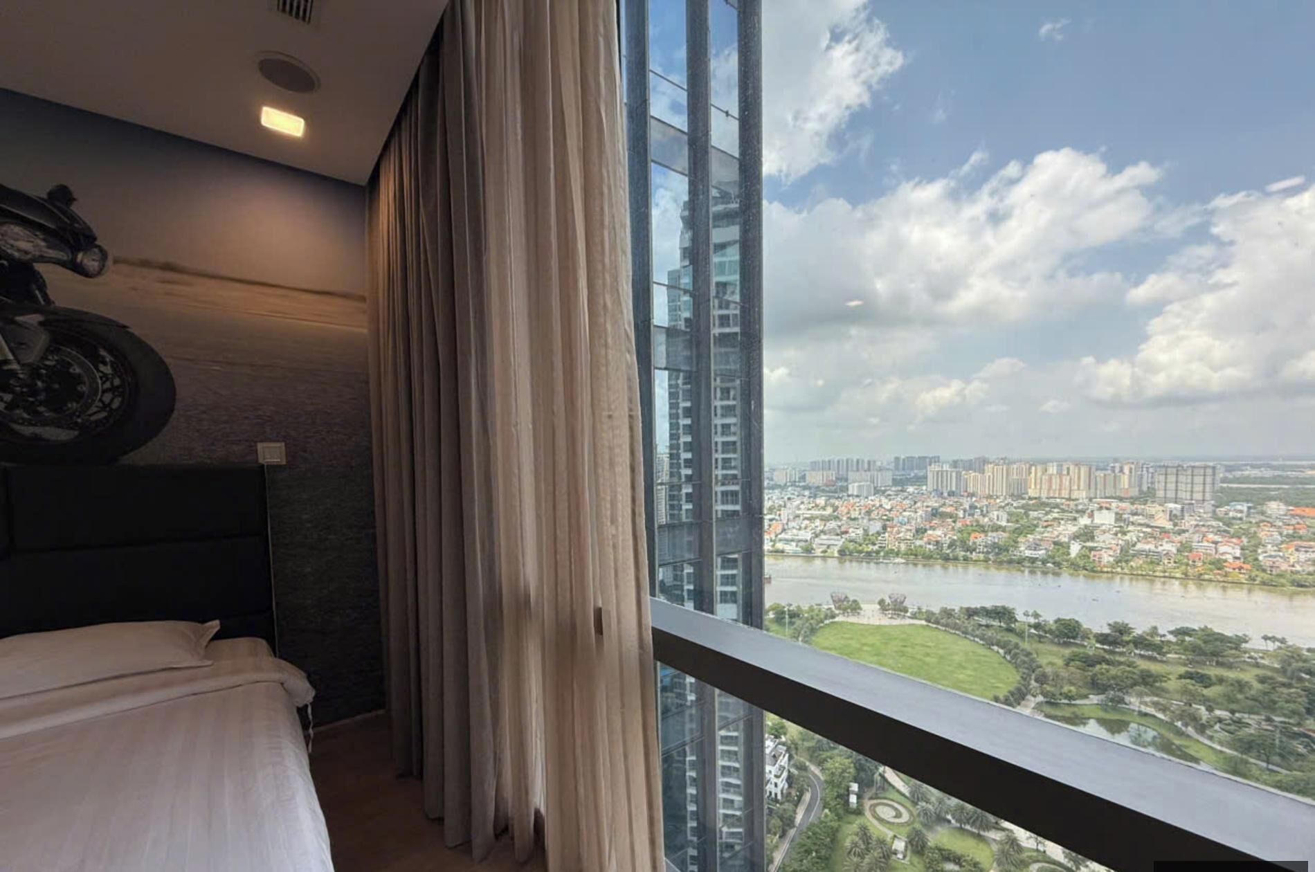 Quarto de hotel com uma janela ampla com vista para a paisagem urbana e um rio.