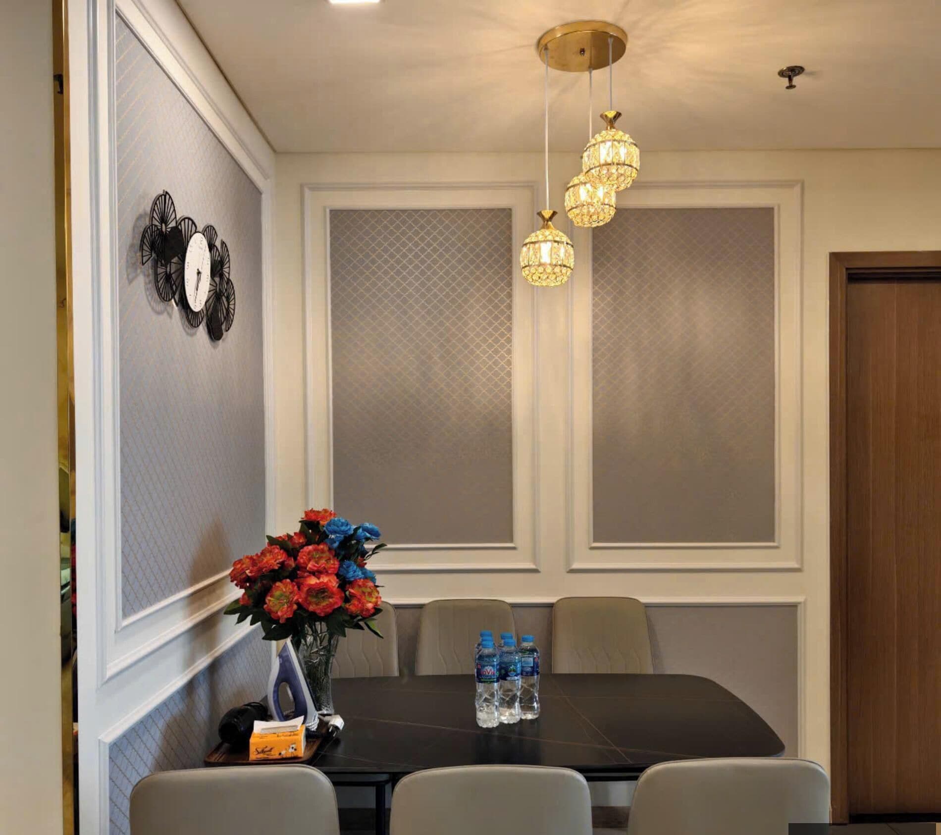 A dining area with a table, chairs, a vase of flowers, and a wall clock.