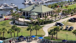 A marina with boats, a building with a green roof, and a pool area with umbrellas.