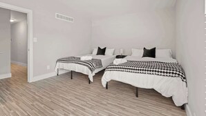 A bedroom with two beds, a small table, and a nightstand.