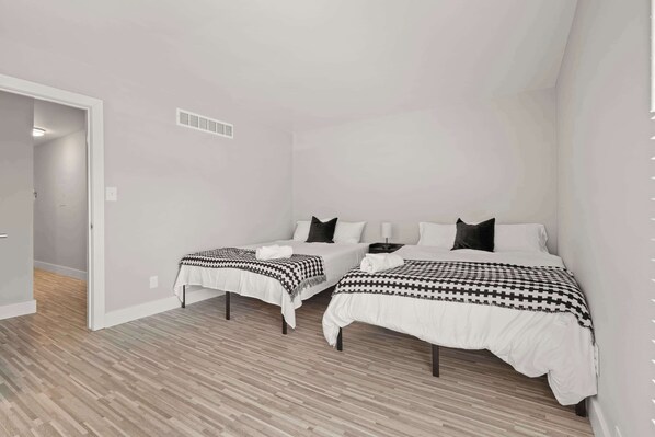 A bedroom with two beds, a small table, and a nightstand. - 2BR Stay Close to Downtown (Rochester Hills)