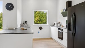 Ett modernt kök med ett stort fönster, ett svart kylskåp och en kaffebryggare.