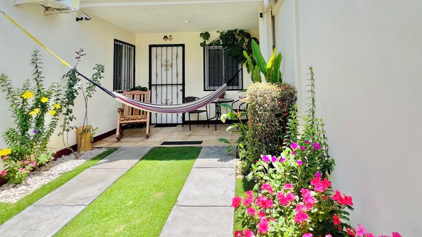A patio with a hammock, a wooden chair, a small table, and potted plants. - Cozy apartment in phenomenal Managua with WiFi, AC, garache and kitchen. (Managua)