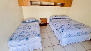 A room with two single beds, each with a floral bedspread, a wooden wardrobe above, and a small wooden nightstand between the beds. - Cozy apartment in phenomenal Managua with WiFi, AC, garache and kitchen. (Managua)