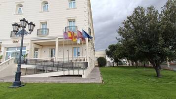 A multi-story building with a balcony, a staircase, and a flag display.