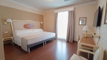 A hotel room with a bed, bedside tables, a desk, and a chair.