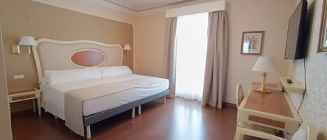 Una habitación de hotel con cama, mesitas de noche, escritorio y una silla.