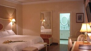 Et hotelværelse med en stor seng, en bænk, et skrivebord og et spejl.