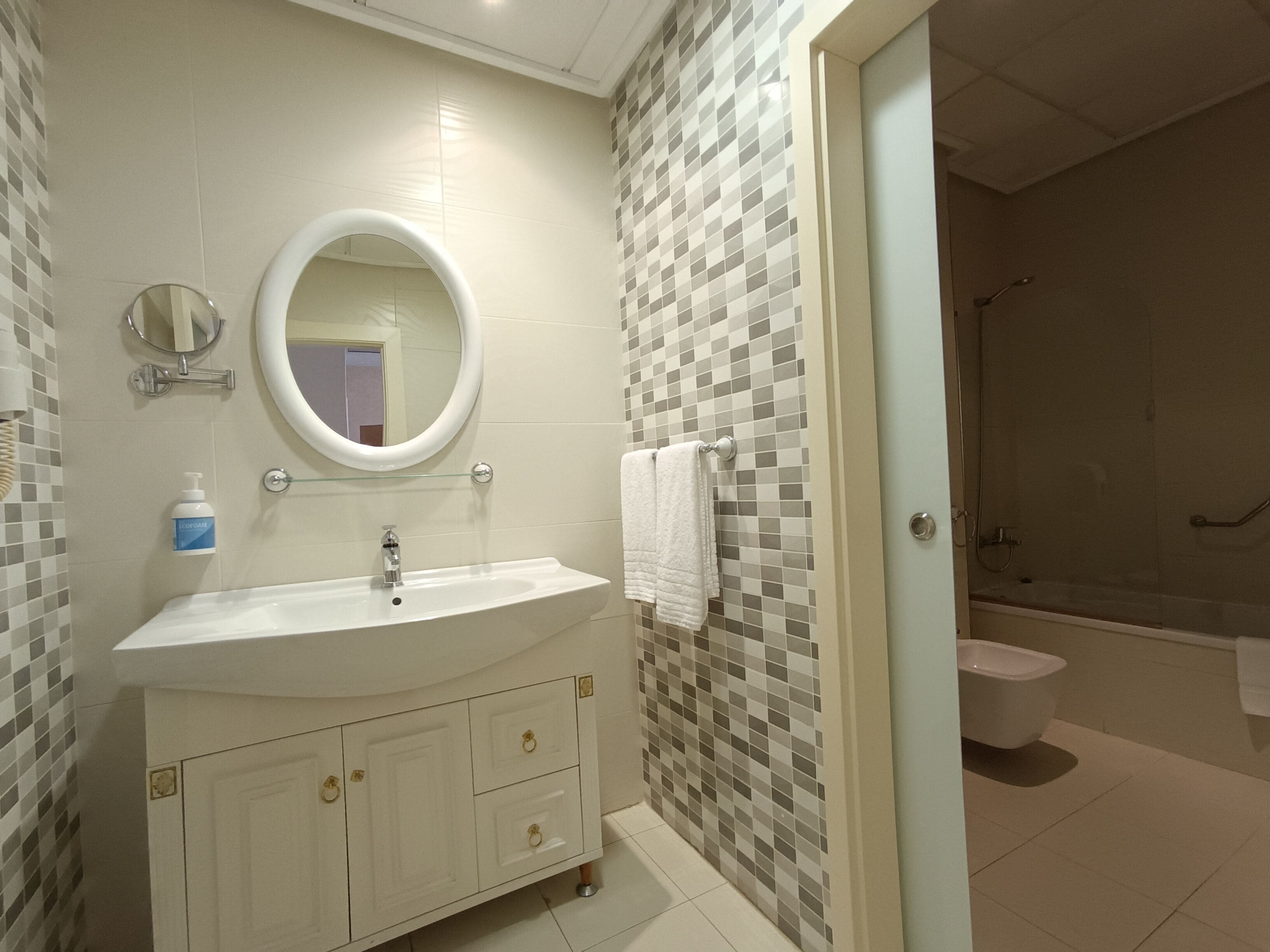 Un baño con lavabo, espejo y paredes de azulejos.