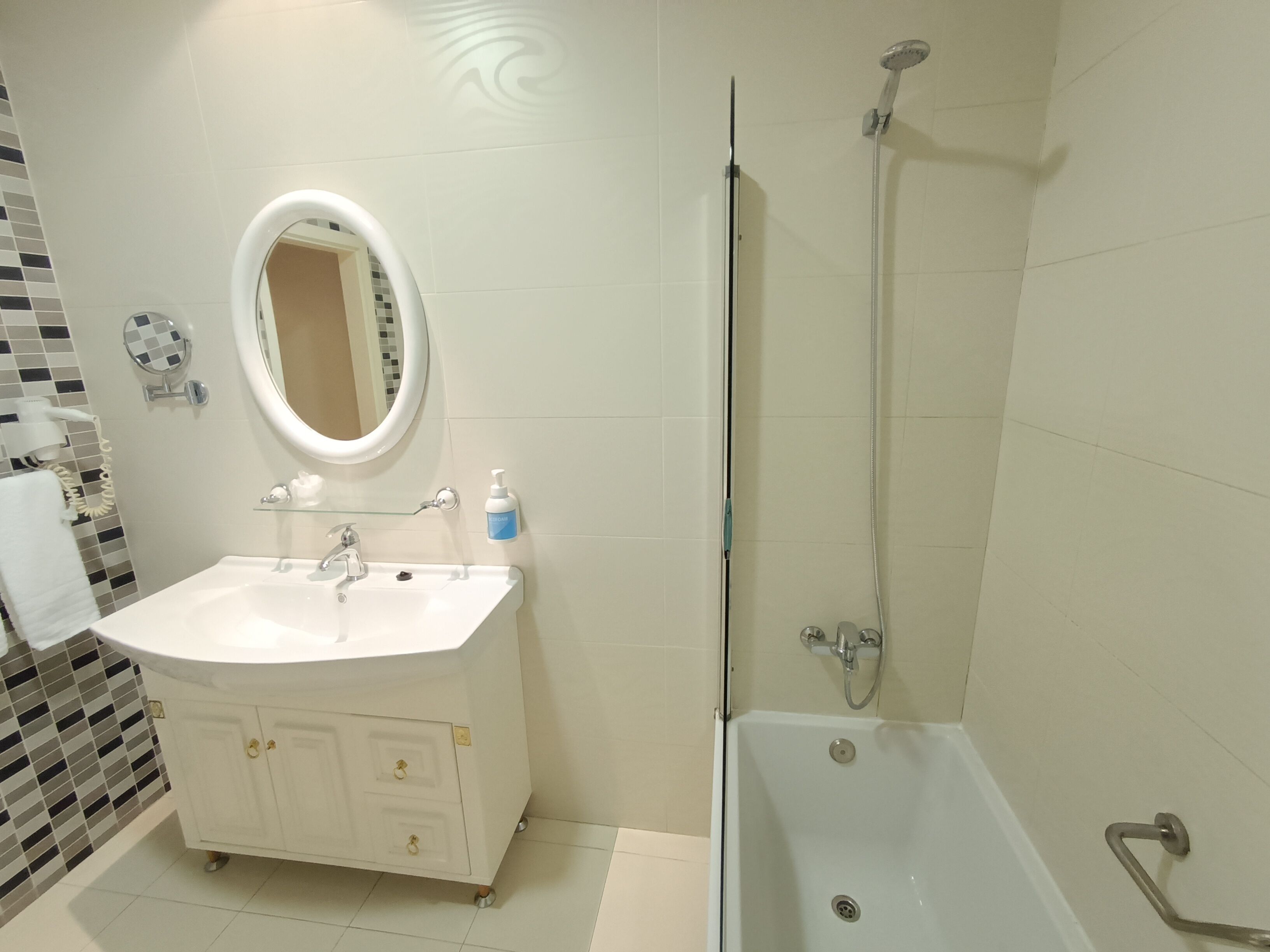 A bathroom with a white sink, mirror, and shower.