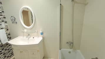 A bathroom with a white sink, mirror, and shower.