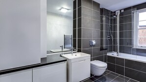 A modern bathroom with a shower, toilet, and sink.