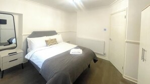 A hotel room with a bed, a bedside table, a mirror, and a wardrobe.