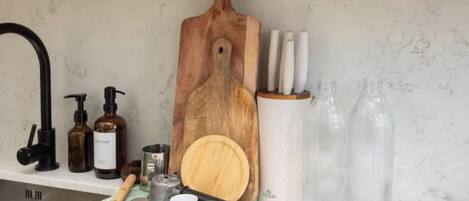Een keukenblad met een houten snijplank, een messenblok, een zeepdispenser en een fles afwasmiddel.
