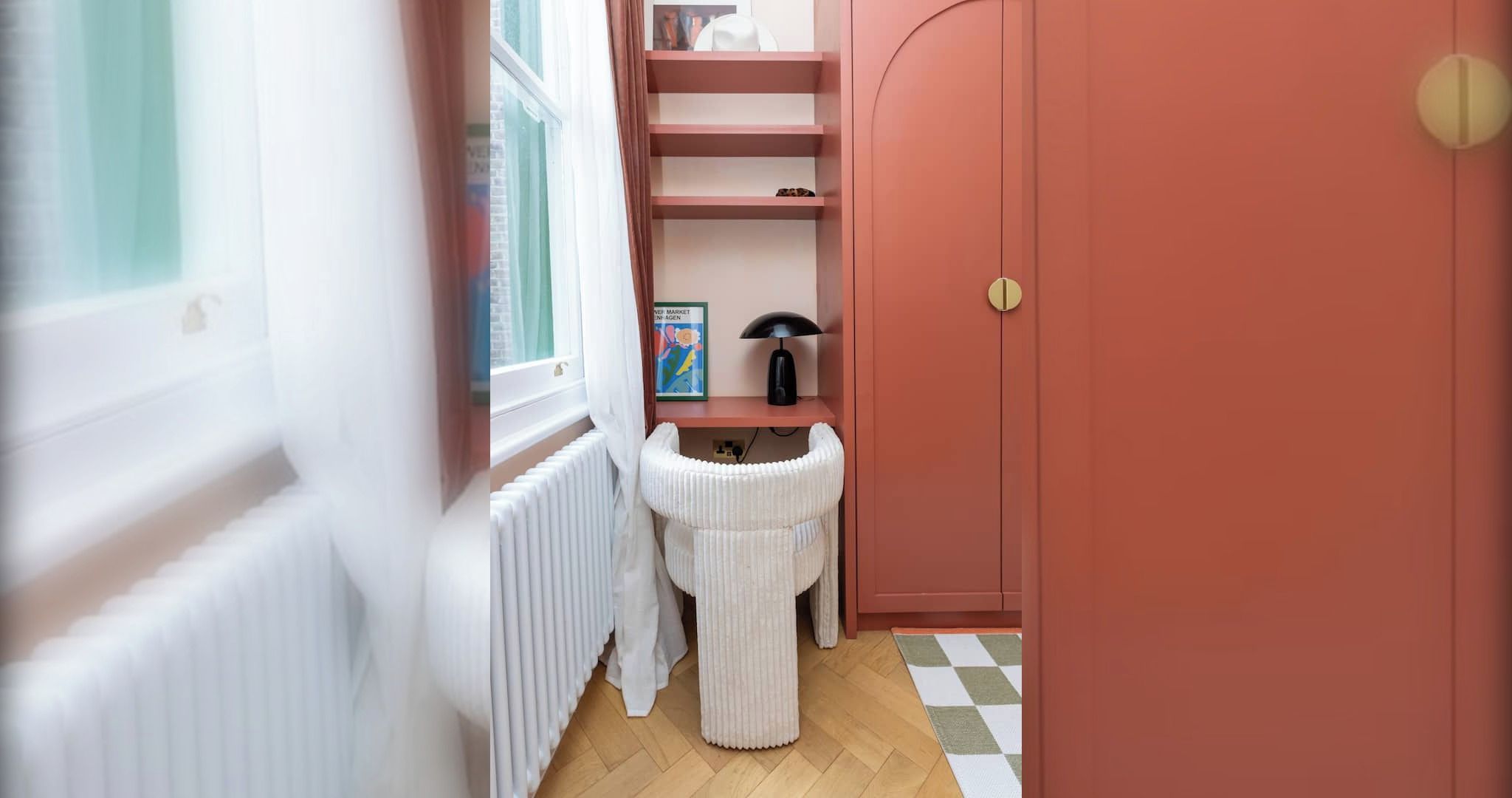 A hallway with a white radiator, a white knitted chair, a shelf with a book and a lamp, and a red door.