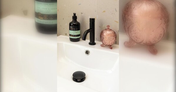 A bathroom sink with a bottle of hand wash soap, a faucet, and a decorative copper vessel.