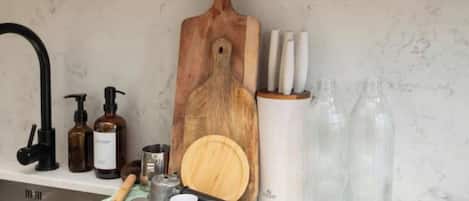 Una encimera de cocina con una tabla de cortar de madera, un bloque de cuchillos, un dispensador de jabón y un juego de tazas medidoras.