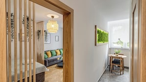 A modern interior with a wooden partition, a sofa, a small table, and a hanging light fixture. - RentPlanet - Apartament Kościuszki (Wroclaw)