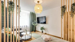Een moderne slaapkamer met een bed, een ronde salontafel, een bank en een aan de muur bevestigde televisie.