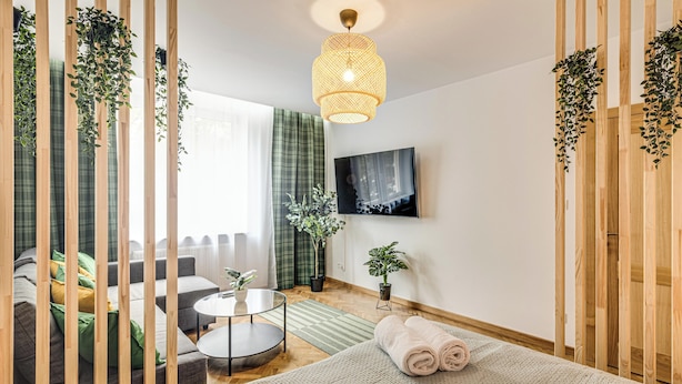 A modern bedroom with a bed, a round coffee table, a sofa, and a TV mounted on the wall. - RentPlanet - Apartament Kościuszki (Wroclaw)