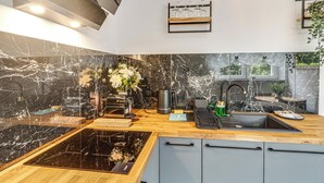 A modern kitchen with a black marble backsplash, wooden countertop, and integrated appliances. - RentPlanet - Apartament Kościuszki (Wroclaw)