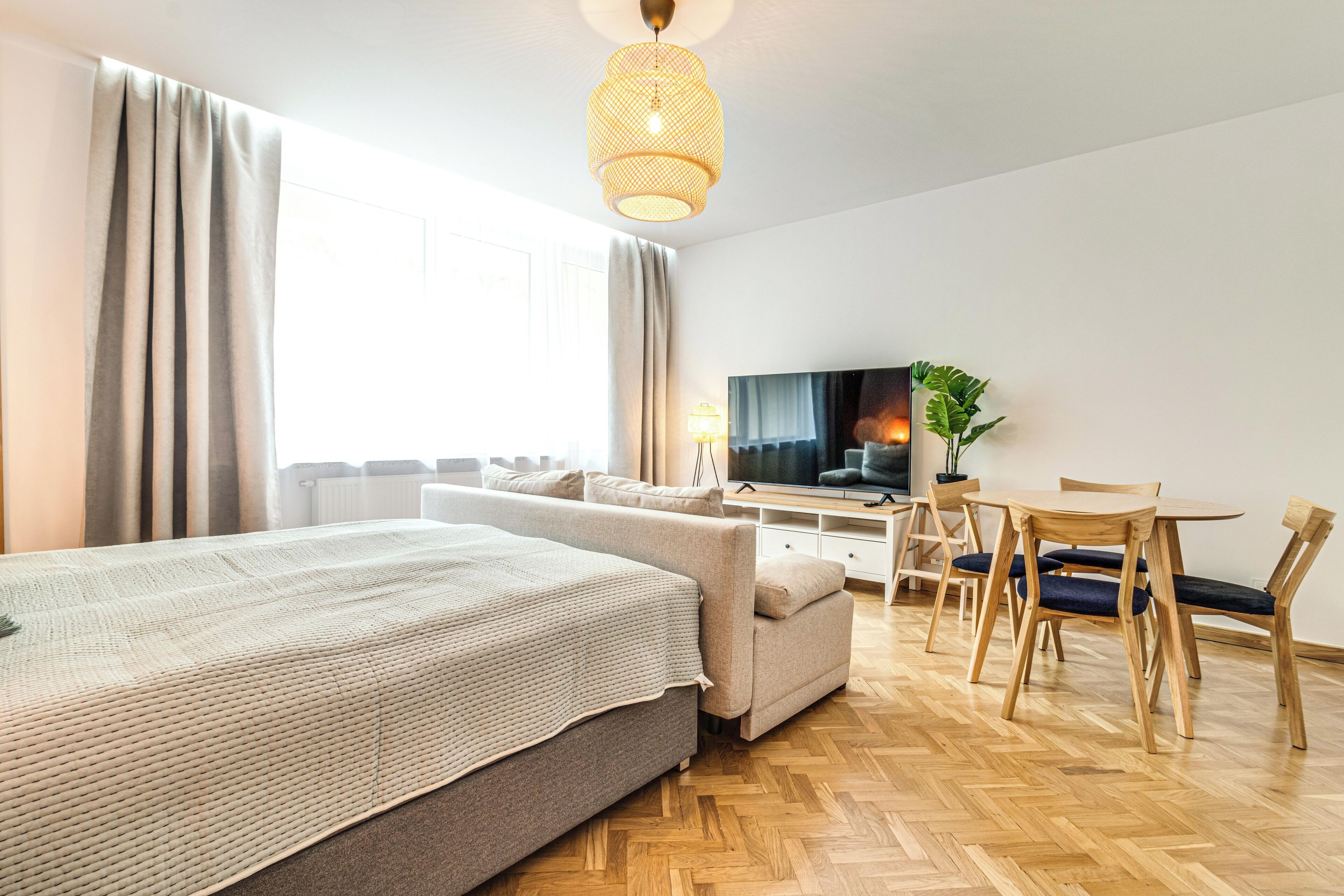 Ett modernt hotellrum med en stor säng, en TV, en matplats och en krukväxt.