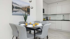 A modern kitchen with white cabinets and a dining area with a table set for four.