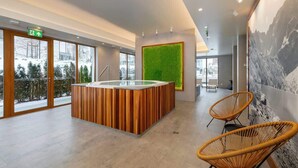 A modern reception area with a wooden reception desk, a green wall feature, and wicker chairs.