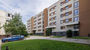 A modern multi-story residential building with a flat roof, large windows, and a central courtyard with a pathway.