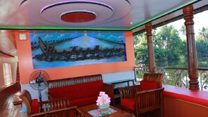 A room with a mural of a boat on water, wooden furniture, and a fan.